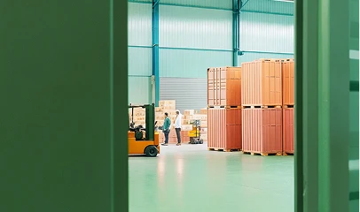 Opérations de manutention de fret dans un centre logistique, avec des conteneurs et des marchandises empilées. 