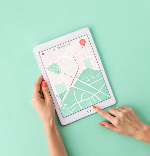 Deux mains tiennent et interagissent avec une tablette affichant une carte avec un itinéraire de livraison Ecolotrans en surbrillance et une épingle de localisation rouge, sur un fond vert clair.
