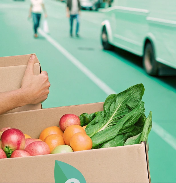 Illustration de livraison de produits frais en milieu urbain : boîte Ecolotrans avec fruits et légumes.